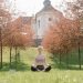 A woman practices meditation outdoors in a tranquil park during fall.